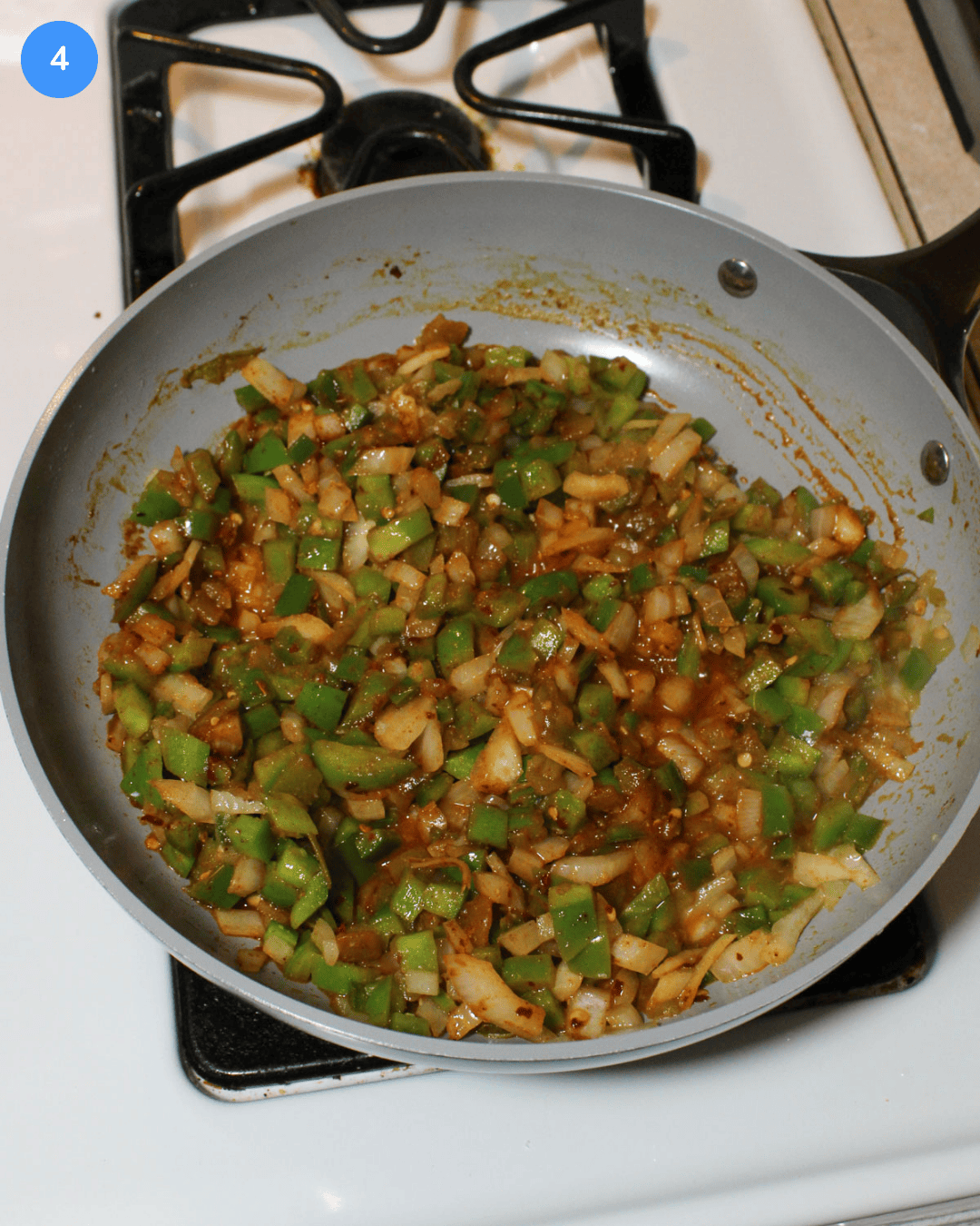 A ceramic skillet of diced veggies and seasonings cooking on the stove.