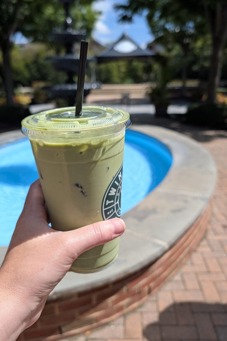 An iced matcha latte in a plastic to go cup with a straw.