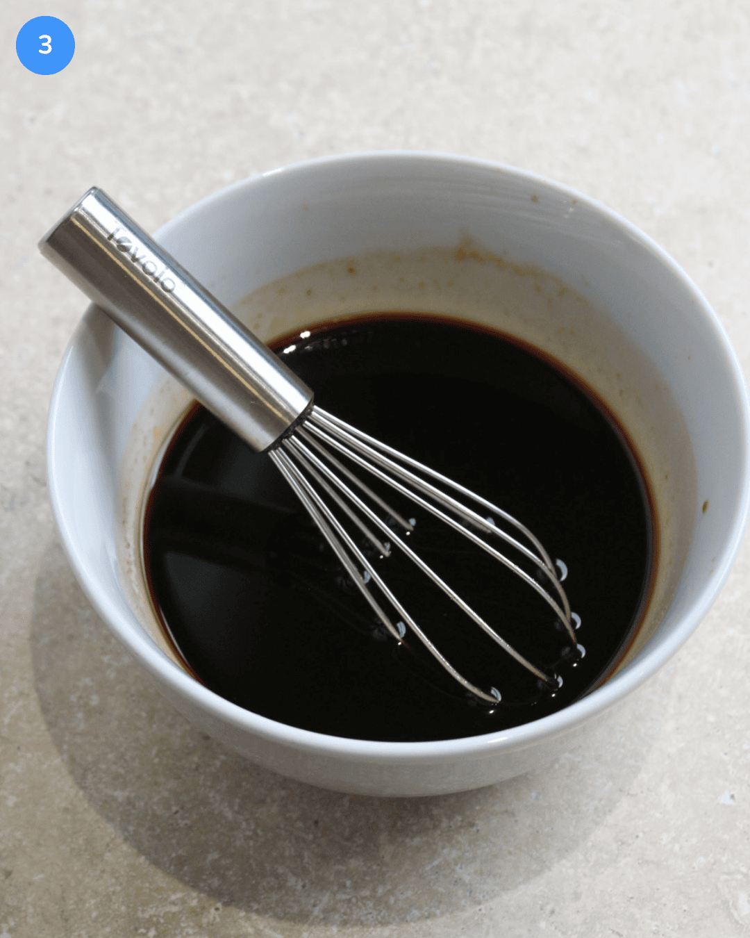 A white ceramic bowl of Thai drunken noodle sauce being whisked in it.