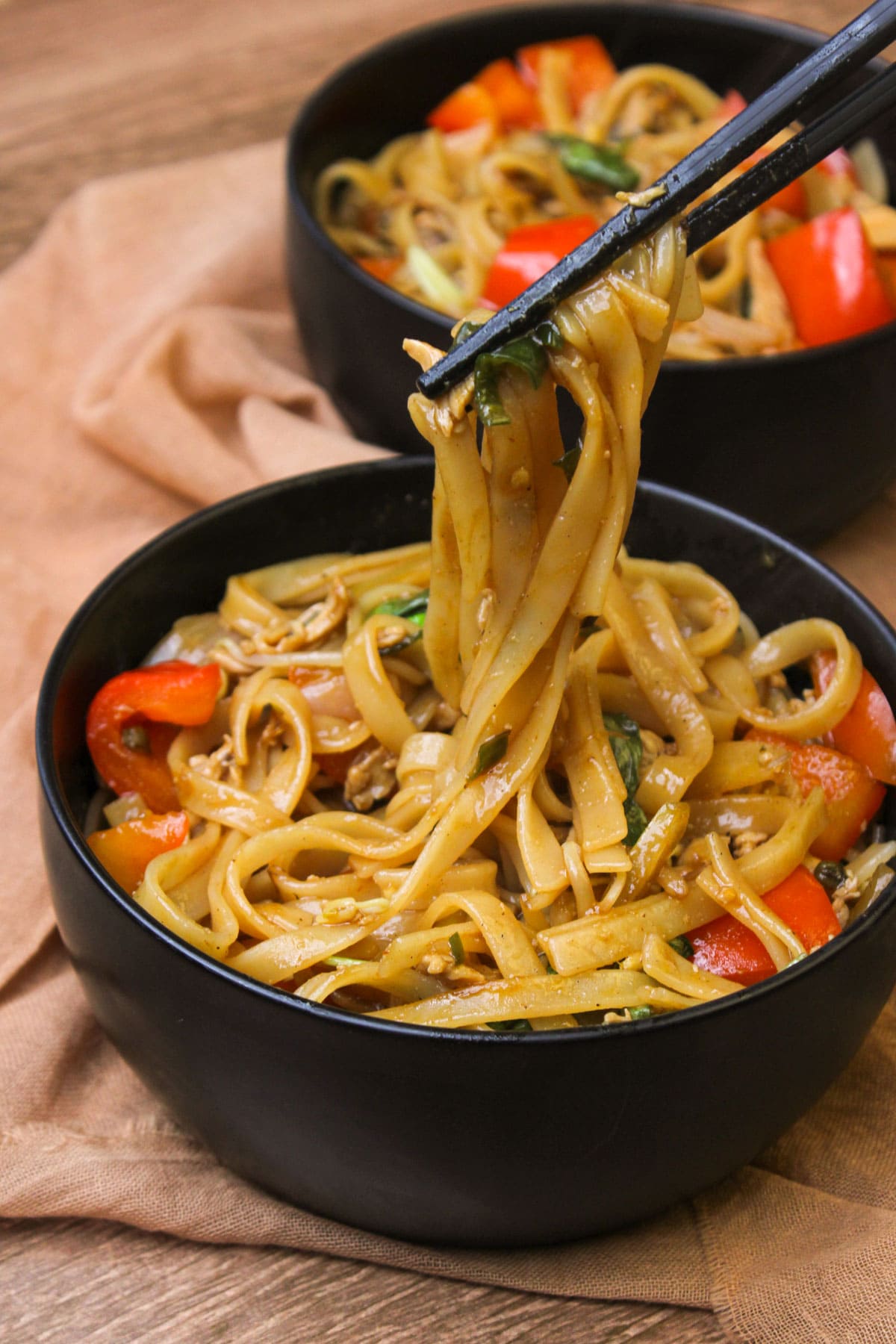Two bowls of freshly cooked Thai drunken noodles with chicken.