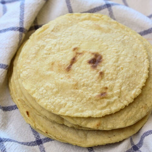 A stack of homemade corn tortillas in a warming towel.