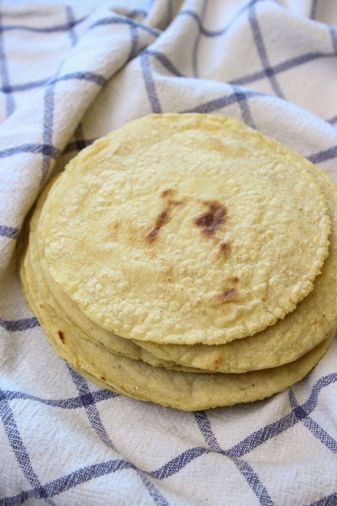 A stack of homemade corn tortillas in a warming towel.