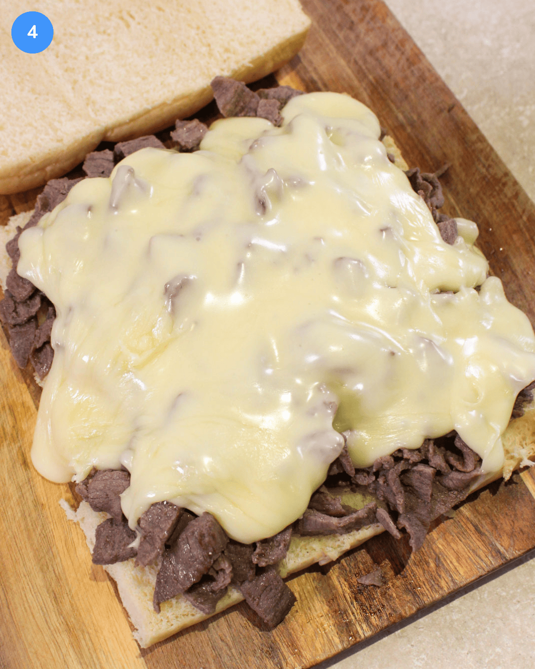 Freshly cooked shaved steak and gooey american cheese sauce piled onto a slab of Hawaiian rolls.