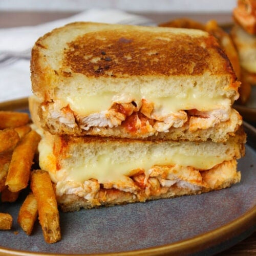 A crispy golden brown sourdough buffalo chicken grilled cheese on a blue stone plate.