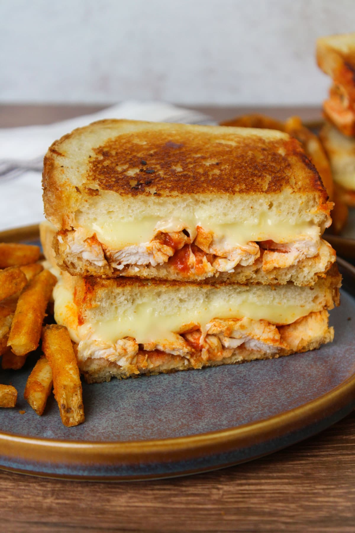 A crispy golden brown sourdough buffalo chicken grilled cheese on a blue stone plate.